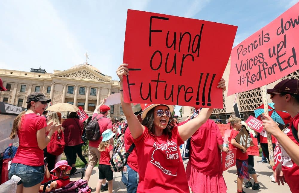 An Arizona teacher holds up a sign in front of the State Capitol during a #REDforED rally on April 26, 2018 in Phoenix, Ariz. Teachers statewide staged a walkout strike on Thursday in support of better wages and state funding for public schools. (Ralph Freso/Getty Images)