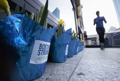 A runner passes flowers placed at the site of the bombing at the Boston Marathon finish line, Saturday, April 15, 2017, in Boston.  Bostonians are marking the fourth anniversary of the deadly 2013 Boston Marathon attacks. (AP Photo/Michael Dwyer)
