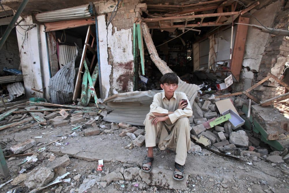 In this 2012 file photo, a Pakistani youth sits amid the rubble of offices destroyed in a car bomb explosion in the Pakistani town of Darra Adam Khel in the troubled Khyber Pakhtunkhwa province bordering Afghanistan. (Mohammad Sajjad/AP)