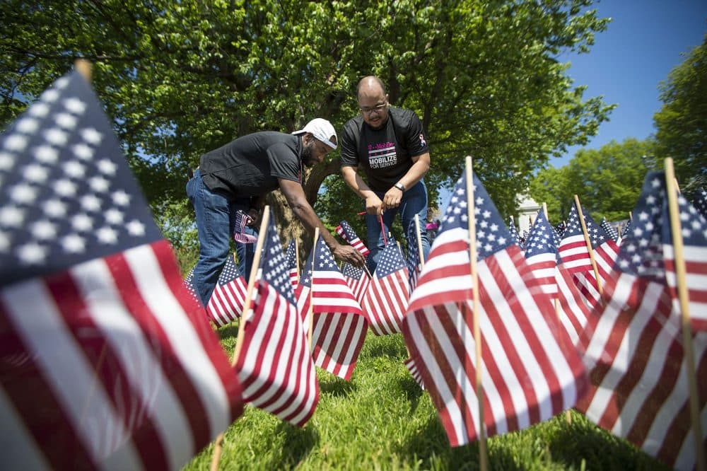 Volunteers Mike Free, left, and Billy Watkins help plant over 37,000 flags in the ground for the annual Memorial Day flag garden in the Boston Common. (Jesse Costa/WBUR)