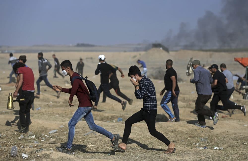 Palestinian protesters run for cover from teargas fired by Israeli troops during a protest at the Gaza Strip's border with Israel, Tuesday, May 15, 2018. Israel faced a growing backlash Tuesday and new charges of using excessive force, a day after Israeli troops firing from across a border fence killed dozens of Palestinians and wounded more than 2,700 at a mass protest in Gaza. (Khalil Hamra/AP)