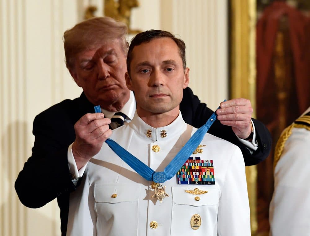 President Trump awards the Medal of Honor to Master Chief Special Warfare Operator Britt K. Slabinski during a ceremony in the White House Thursday. Slabinski oversaw a daring 2002 assault and rescue mission on a snowy Afghanistan mountaintop and carried a &quot;seriously wounded teammate down a sheer cliff face&quot; while leading &quot;an arduous trek across one kilometer of precipitous terrain, through waist-deep snow while continuing to call fire on the enemy.&quot; (Susan Walsh/AP)