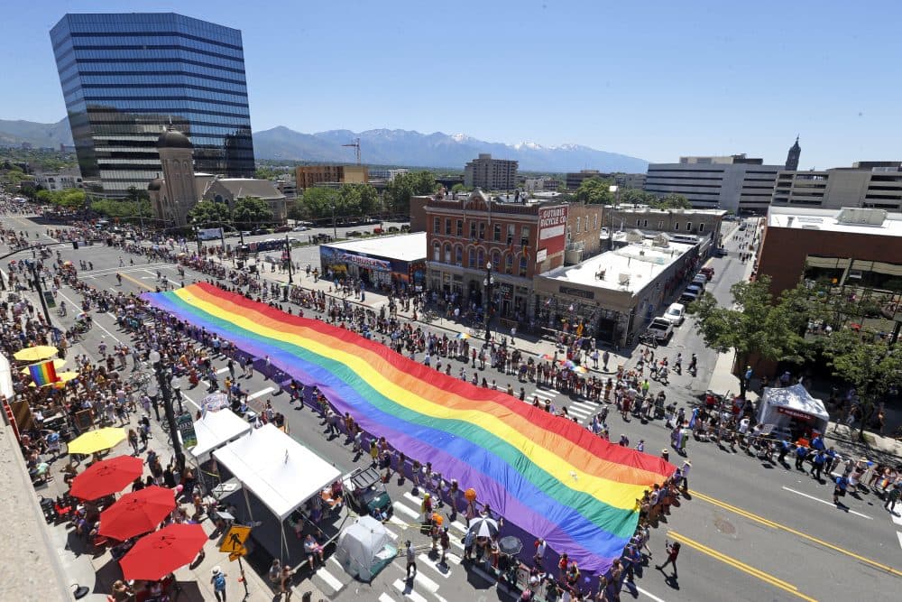 In this Sunday, June 3, 2018, photo, people carry a flag during the Utah Pride parade in Salt Lake City. Salt Lake City police are looking for leads after a man was allegedly attacked while trying to defend several gay men being chased after the Utah Pride Festival. (Rick Bowmer/AP)