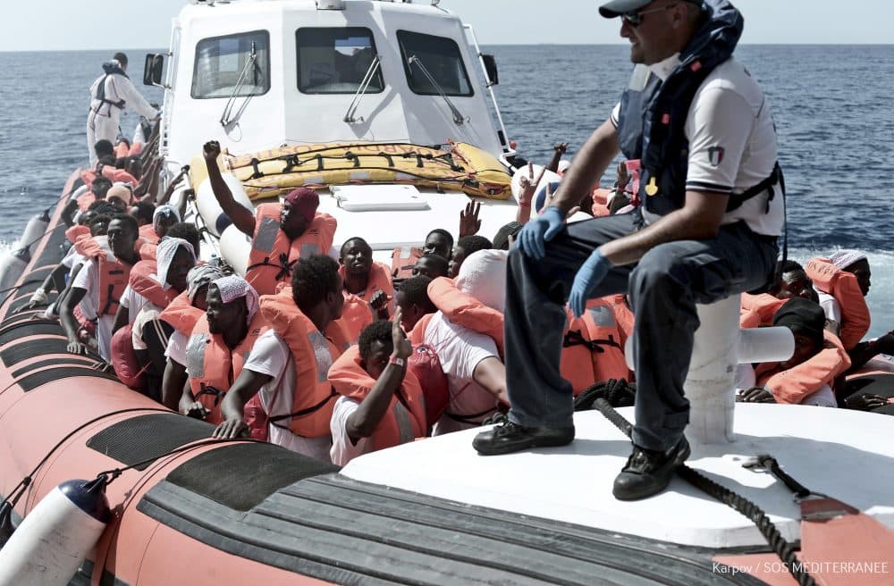 This June 12, 2018 photo released Wednesday, June 13, 2018 by French NGO &quot;SOS Mediterranee&quot; shows migrants waving after being transferred from the Aquarius ship to Italian Coast Guard boats, in the Mediterranean Sea. Italy dispatched two ships Tuesday to help take 629 migrants stuck off its shores on the days-long voyage to Spain in what is forecast to be bad weather, after the new populist government refused them safe port in a dramatic bid to force Europe to share the burden of unrelenting arrivals. (Kenny Karpov/SOS Mediterranee via AP)