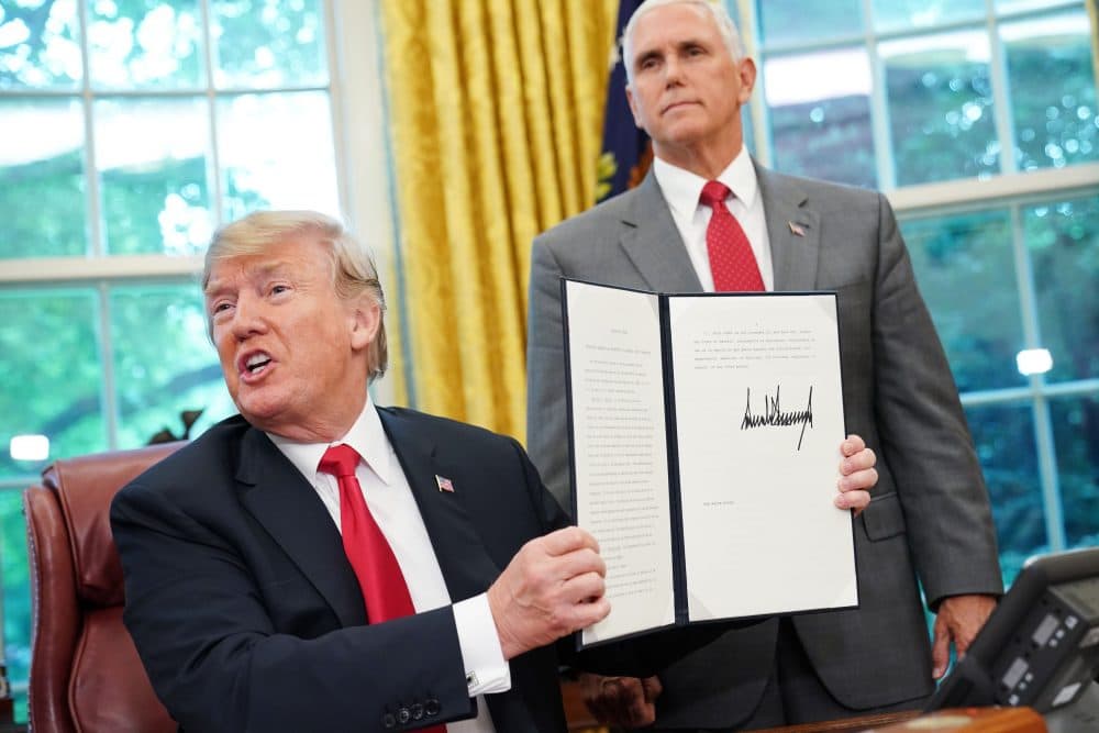 Watched by Vice President Mike Pence, President Trump shows an executive order on immigration signed in the Oval Office of the White House on June 20, 2018 in Washington, D.C. (Mandel Ngan/AFP/Getty Images)