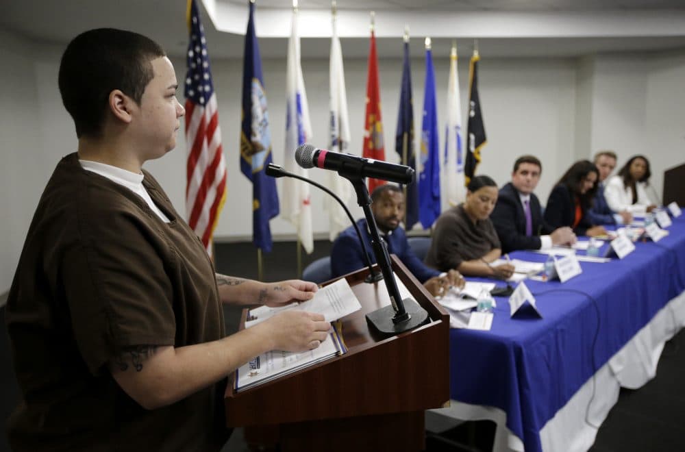 Chante Graham, left, of Fall River, an inmate at Suffolk County House of Correction, presents a question to six candidates for Suffolk County district attorney, during a forum at the jail Tuesday. The six candidates for Suffolk DA are, seated beginning second from left, Evandro Carvalho, Rachael Rollins, Greg Henning, Shannon McAuliffe, Michael Maloney, and Linda Champion. (Steven Senne/AP)