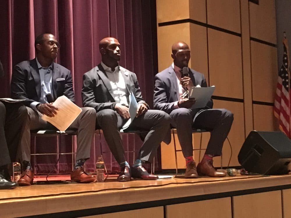 From left, Matthew Slater and Jason McCourty listen as Patriots teammate Devin McCourty asks a question to Suffolk County DA candidates about criminal justice reform. (Shira Springer/WBUR)