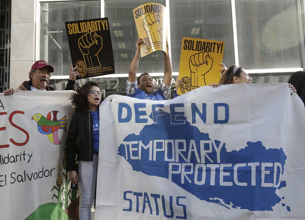 Supporters of temporary protected status immigrants hold signs and cheer before a March, 2018 news conference in San Francisco announcing a lawsuit against the Trump administration over its decision to end TPS. (Jeff Chiu/AP)