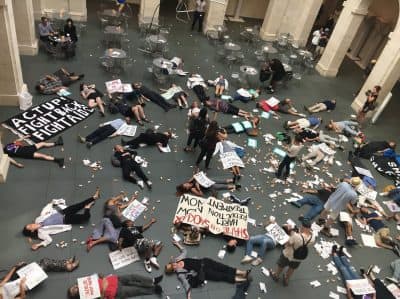 Protesters stage a &quot;die-in&quot; inside Harvard's Arthur M. Sackler Museum to protest the Sackler family's ties to Purdue Pharma and the opioid crisis. (Justin Kaplan/WBUR)