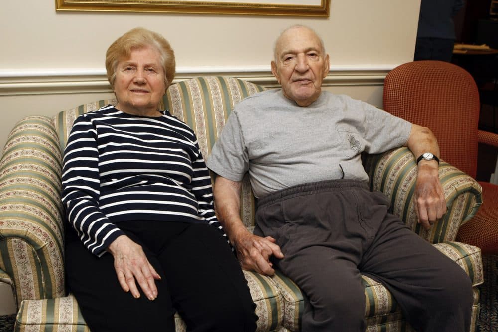 Jeannette Zeltzer, 81 and her new boyfriend Max Rakov, 92, hold hands while sitting on a couch at the assisted living facility where they live in Newton, Mass. Rakov suffers from Alzheimer's. (Greg M. Cooper/AP)