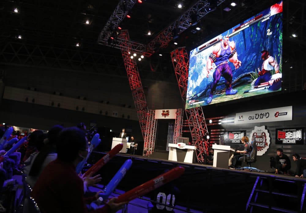 In this Feb. 10, 2018 photo, a crowd watches the final of &quot;Street Fighter&quot; during an esports event at Makuhari Messe in Chiba near Tokyo. A crowd cheers, banging on balloons, in front of glitzy stages, each with a giant screen. (Yuri Kageyama/AP)
