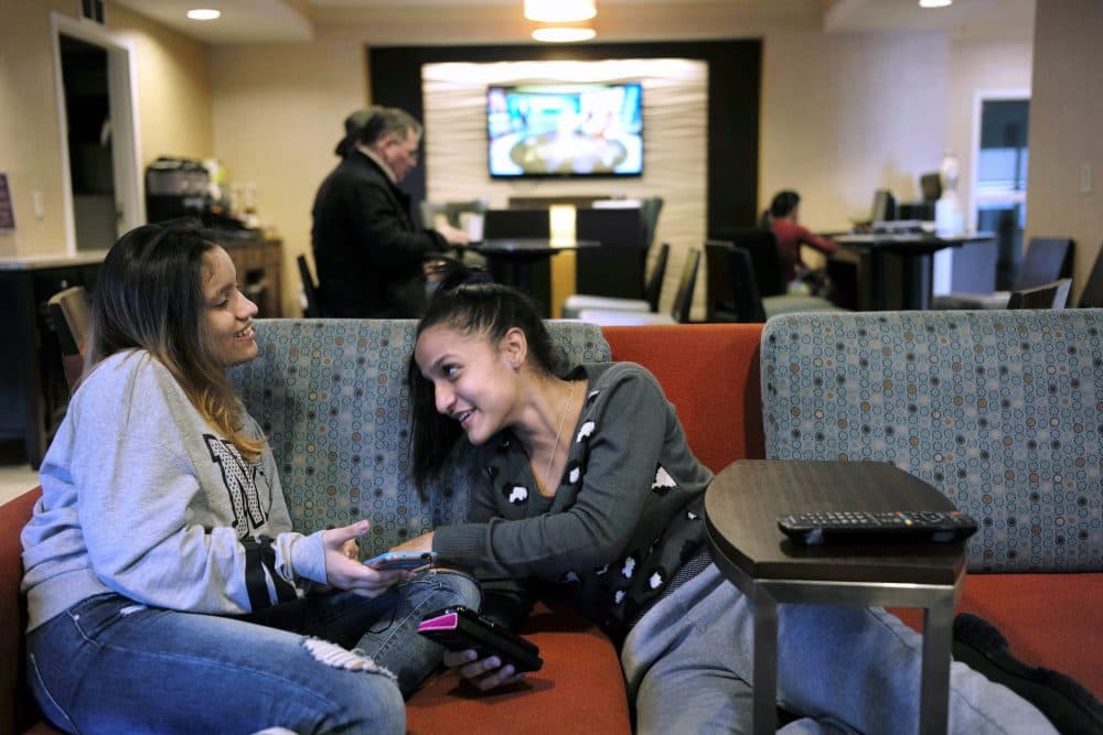 In this Feb. 27 file photo, 15-year-old Alanis Rodriguez, left, of Canovanos, Puerto Rico, and 14-year-old Bethel Sanchez, right, of Isabela, Puerto Rico, spend time together in a hotel lobby in Dedham, where they lived temporarily after Hurricane Maria hit the island in September. (Steven Senne/AP)