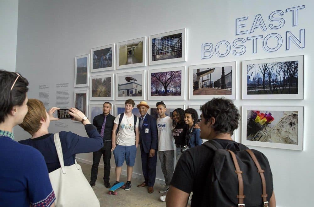 Visitors to the inaugural exhibition of the ICA Watershed pose for a photo in front of a wall of photographs of East Boston by teens from the ICA's digital photography program, June 2018. (Robin Lubbock/WBUR)