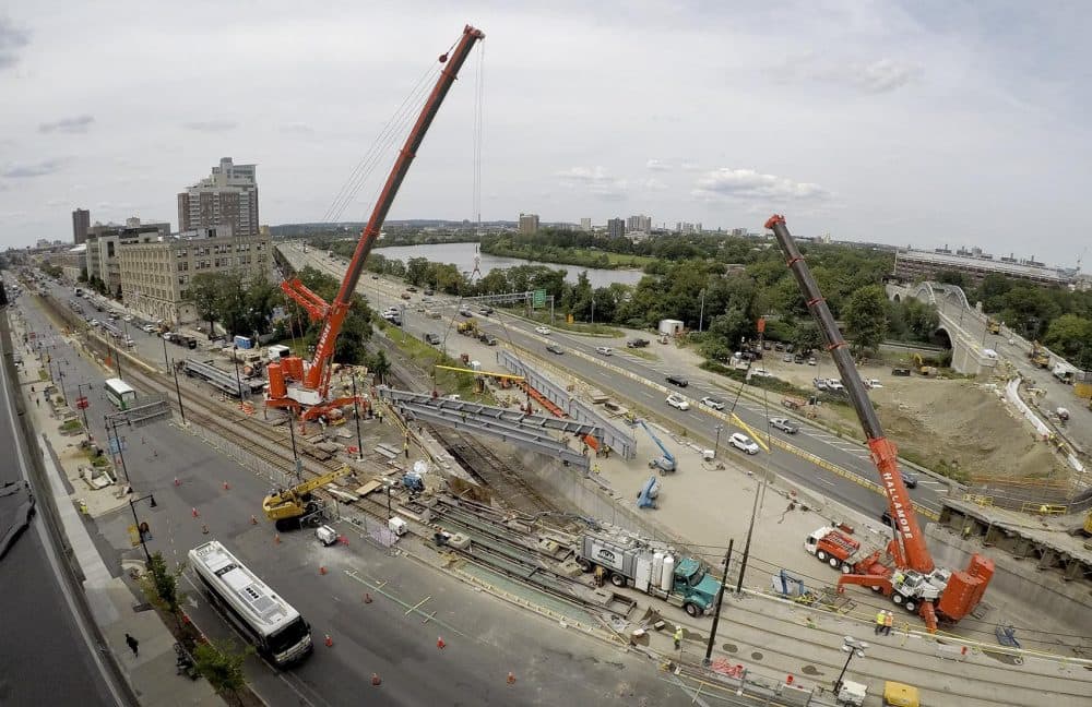 A crane lowers a new steel beam into place as part of construction to replace the westbound side of the Commonwealth Avenue Bridge. (Robin Lubbock/WBUR)