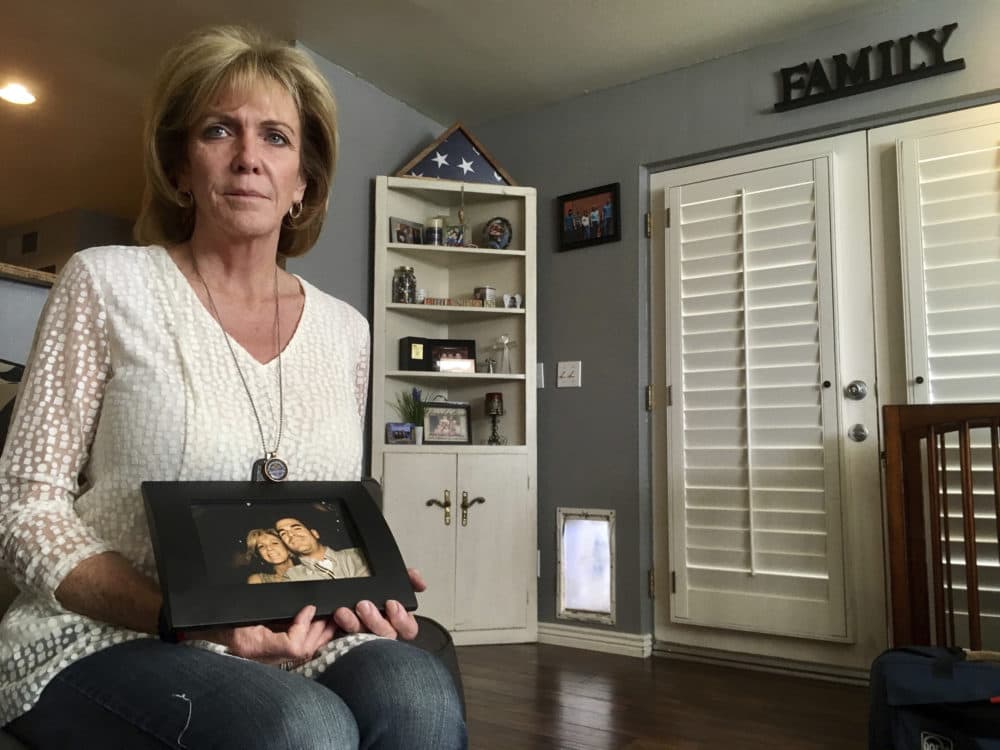Mary Ann Mendoza poses for a photograph while holding a framed picture of herself and her son, Brandon Mendoza, on Thursday, March 2, 2017, at her home in Mesa, Ariz. Mendoza's son, a Mesa police officer, was killed on May 12, 2014, in a head-on collision with a man who authorities say was intoxicated and an immigrant in the country illegally. Both Brandon Mendoza and the other diver were killed in the crash. (Brian Skoloff/AP)