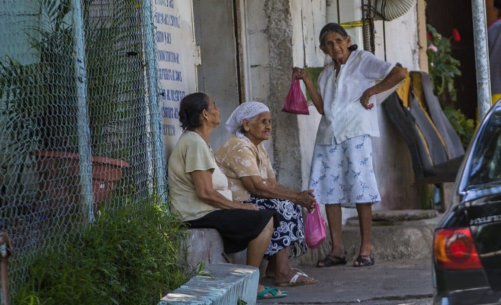 Three women wait outside of the Iglesia Profetica Esposa del Cordero la Central in San Salvador. (Jesse Costa/WBUR)