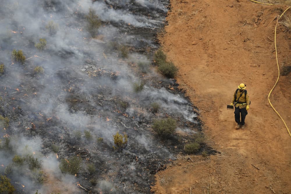 A firefighter walks along a containment line while battling a wildfire Saturday, July 28, 2018, in Redding, Calif. (Marcio Jose Sanchez/AP)