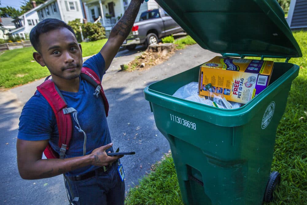 Lowell recycling enforcement coordinator Bora Chhun checks a recycling bin for non-recycable items on Beacon Street in Lowell. (Jesse Costa/WBUR)