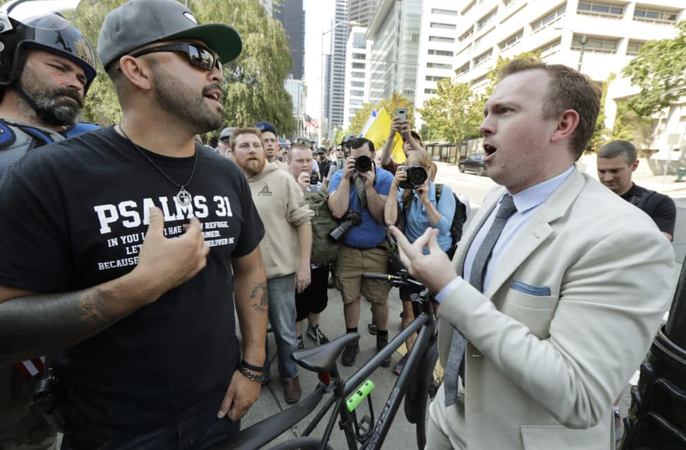 Joey Gibson, left, founder of the Patriot Prayer group, argues with a bystander at right as Gibson's group marched following a rally supporting gun rights, Saturday, Aug. 18, 2018, at City Hall in Seattle. (Ted S. Warren/AP)