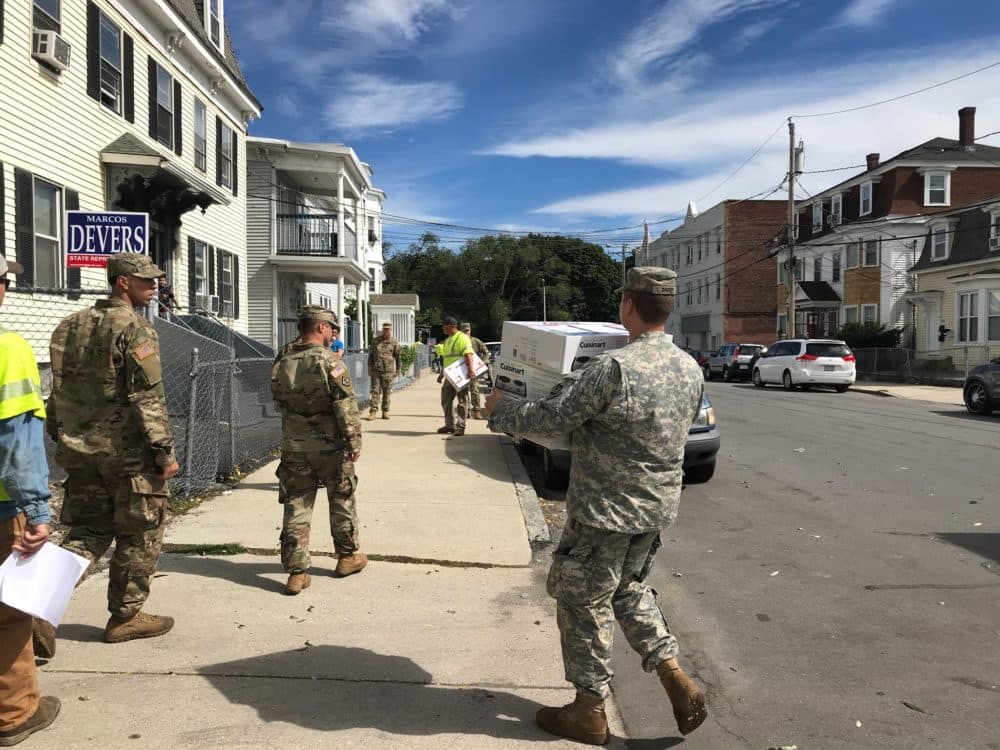 National Guardsmen walk through the streets of Lawrence on Saturday, distributing hot plates to residents who were left without gas. (Quincy Walters/WBUR)
