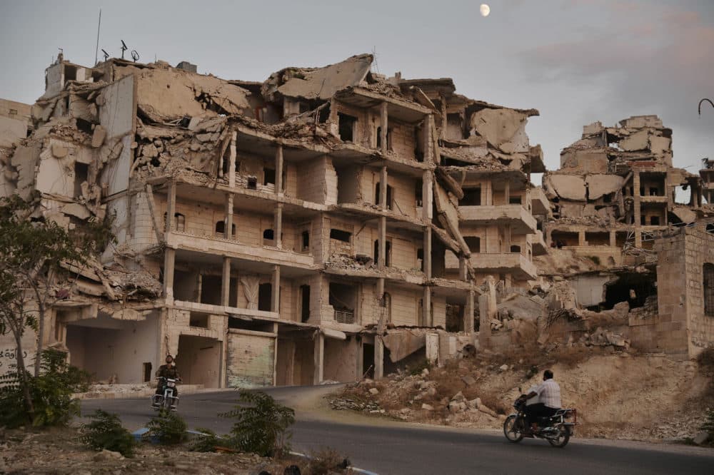 FILE - In this Sept. 20, 2018, file photo, motor cycles ride past buildings destroyed during the fighting in the northern town of Ariha in Idlib province, Syria. As world leaders talk peace at the U.N. this week, the Syrian region of Idlib clings to fragile hope that diplomacy will help avert a blowout battle over the countrys last rebel stronghold. (Ugur Can/DHA via AP, File)