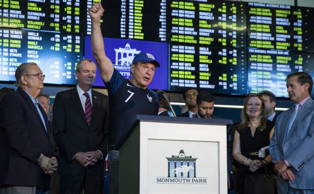 Former New Jersey State Senator Raymond Lesniak, the legal champion in the Supreme Court decision to legalize gambling, raises his hand while speaking on June 14, 2018 before Governor Phil Murphy to placed the first bet at the Monmouth Park Sports Book on the first day of legal sports betting in the state in New Jersey. (DOMINICK REUTER / AFP/Getty Images)