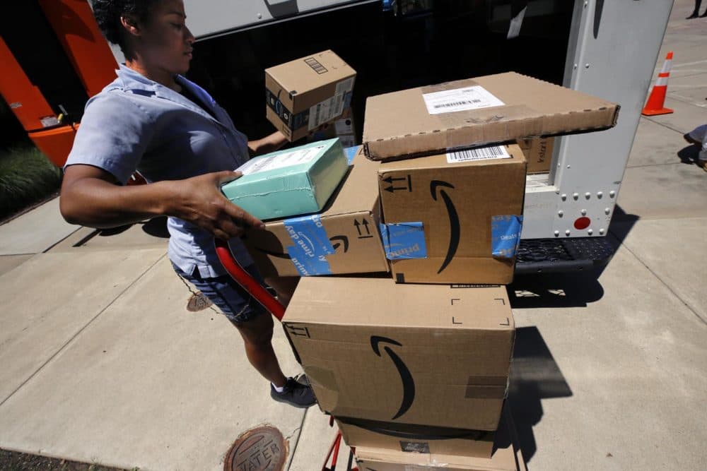 A U.S. postal carrier delivers Amazon orders to an apartment complex in downtown Pittsburgh in July of 2019. (Gene J. Puskar/AP)