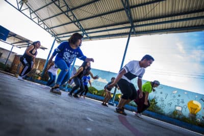 Volunteers for Glasswing International lead members of the Glee club in a dance routine at a school in Las Palmas, San Salvador, El Salvador. (Jesse Costa/WBUR)