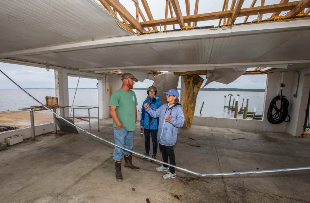 Here & Now's Robin Young, right, and Karyn Miller-Medzon interview T.J. Ward at his oyster processing facility that was gutted by Hurricane Michael in Apalachicola, Fla. (Mark Wallheiser for Here & Now)