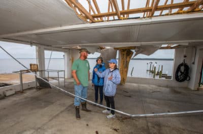 Here & Now's Robin Young, right, and Karyn Miller-Medzon interview T.J. Ward at his oyster processing facility that was gutted by Hurricane Michael in Apalachicola, Fla. (Mark Wallheiser for Here & Now)