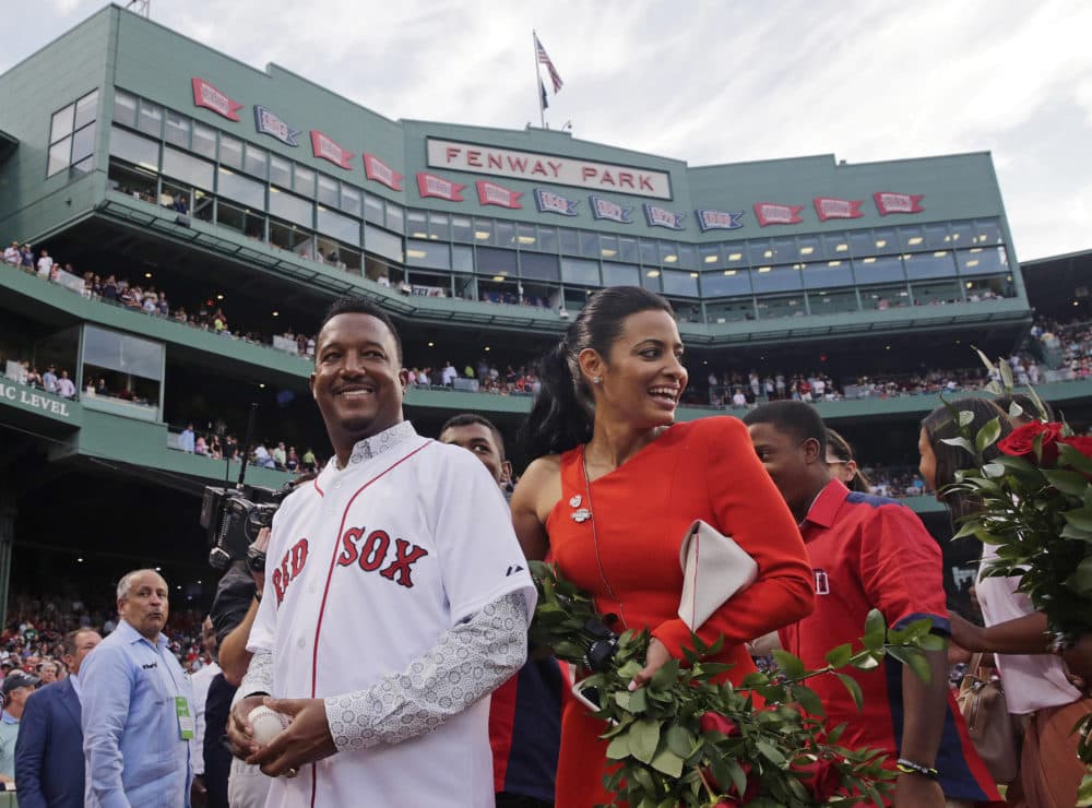 Baseball Hall of Fame member and former Boston Red Sox player Pedro Martinez, left, walks off the field with his wife, Carolina, during a ceremony where his jersey was retired prior to a baseball game against the Chicago White Sox at Fenway Park in Boston, July 28, 2015. (Charles Krupa/AP)