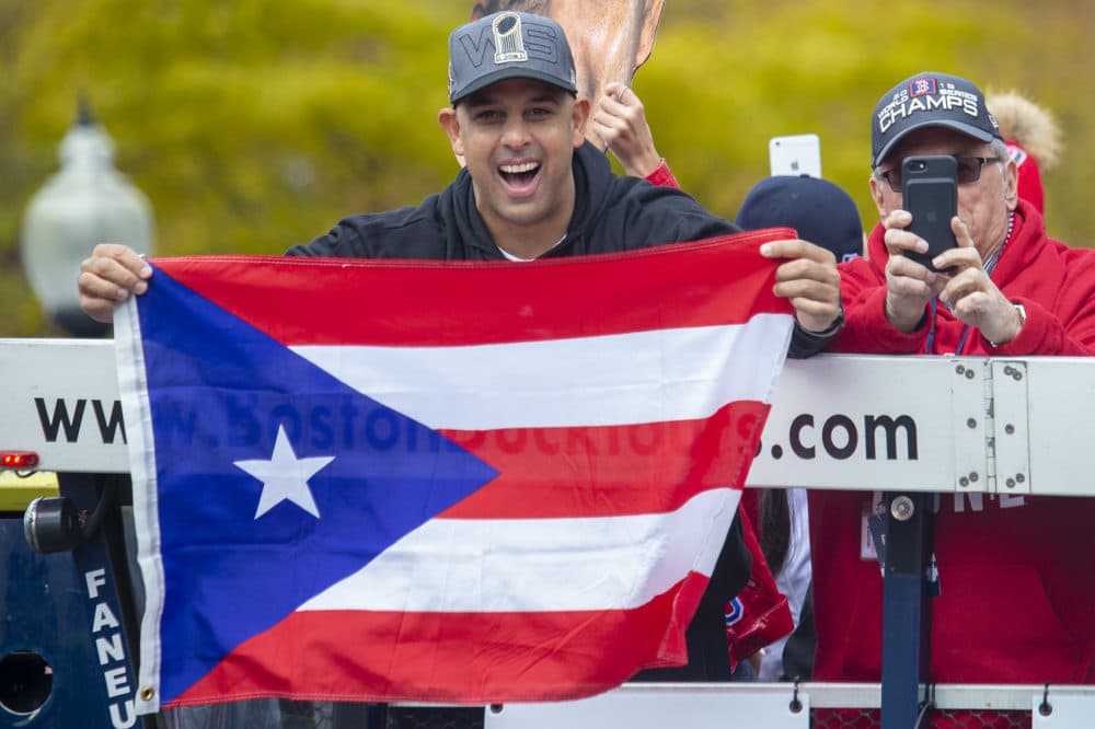 Red Sox manager Alex Cora holds up a flag from his native home of Puerto Rico. (Jesse Costa/WBUR)