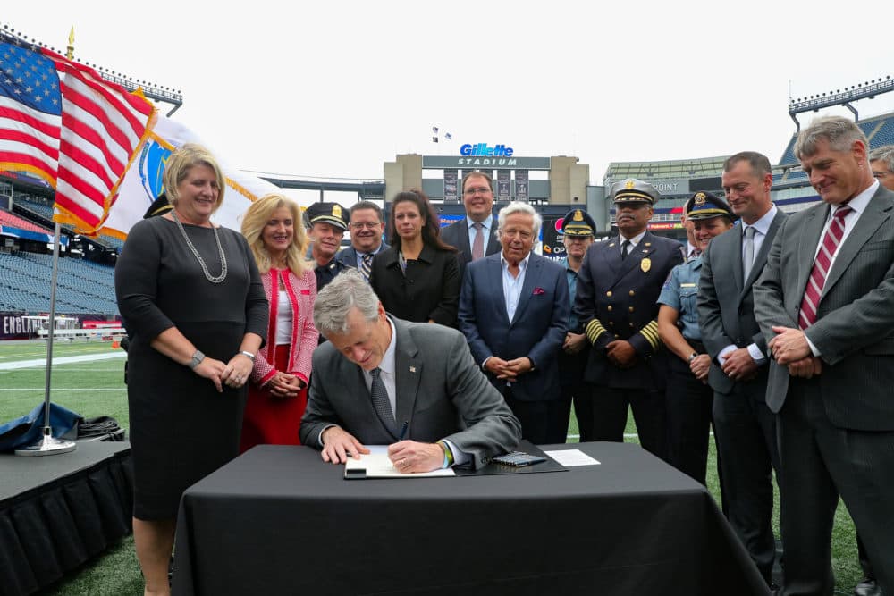 Gov. Charlie Baker signs an executive order Thursday at Gillette Stadium, creating the Massachusetts Large Venue Security Task Force. He was flanked by Secretary of Public Safety and Security Daniel Bennett, Undersecretary of Homeland Security Patrick McMurray, Patriots owner Robert Kraft, TD Garden President Amy Latimer and several members of the task force. (Courtesy of Eric Adler/New England Patriots)
