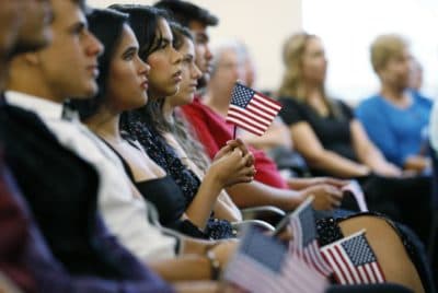 New citizens hold an American flag as they listen during a naturalization ceremony at the U.S. Citizenship and Immigration Services Kendall Field Office, Thursday, Aug. 30, 2018, in Miami. (Wilfredo Lee/AP)