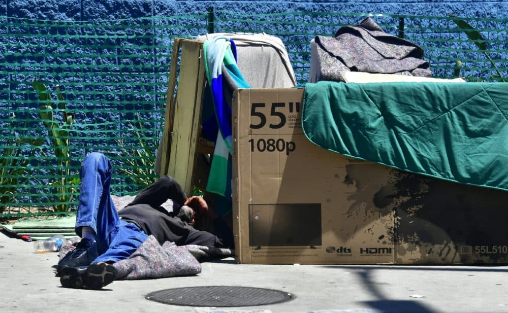 A homeless man sleeps beside his makeshift temporary shelter on a street in downtown Los Angeles in June 2018. (Photo by Frederic J. BROWN / AFP)        (Photo credit should read FREDERIC J. BROWN/AFP/Getty Images)