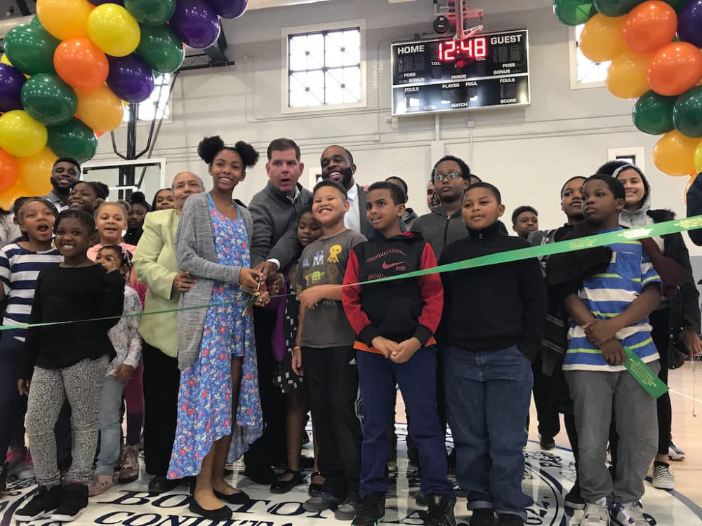 Mayor Marty Walsh, surrounded by local kids, cuts the ribbon at the reopening of the renovated Roxbury branch of Boston Centers for Youth and  Families on Sat., Oct. 13. (Quincy Walters/WBUR)