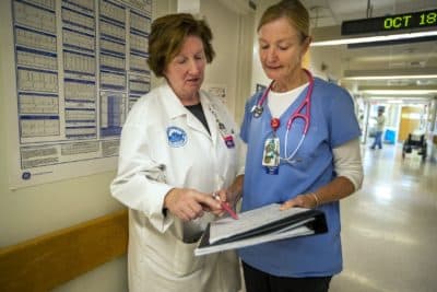 Theresa Capodilupo, left, a nurse director, and Brenda Pignone, a bedside nurse, review the daily patient assignment sheet for White 7, a post-surgery and trauma unit at Massachusetts General Hospital. (Jesse Costa/WBUR)