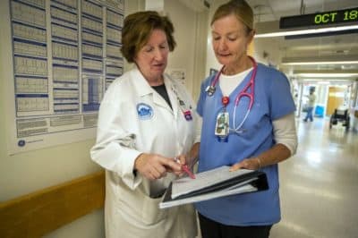 Theresa Capodilupo, a nurse director and Brenda Pignone, a bedside nurse, review the daily patient assignment sheet for a post-surgery and trauma unit at Massachusetts General Hospital. (Jesse Costa/WBUR)