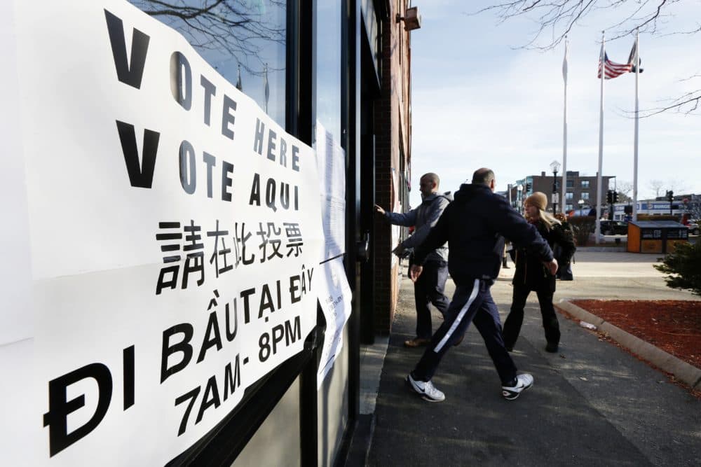 Voters arrive and depart at a polling station for Massachusetts' primary election in the East Boston neighborhood of Boston in 2016. Voting materials appear here in several languages. (Michael Dwyer/AP)