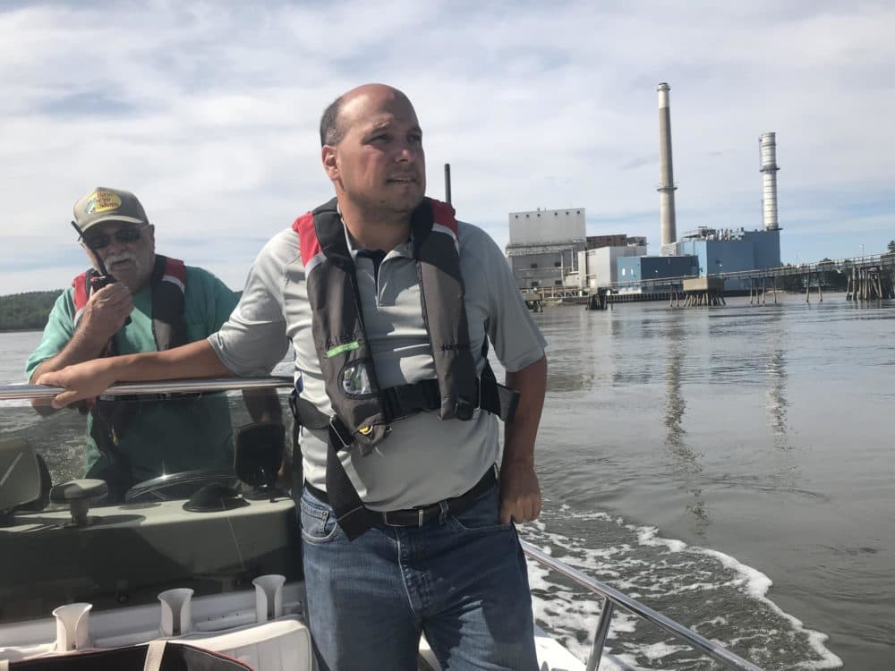 Richard Rotella, Bucksport’s economic development director, says an indoor salmon farm proposed for the old mill behind him will add some 21st century jobs to the town. (Fred Bever/Maine Public Radio)