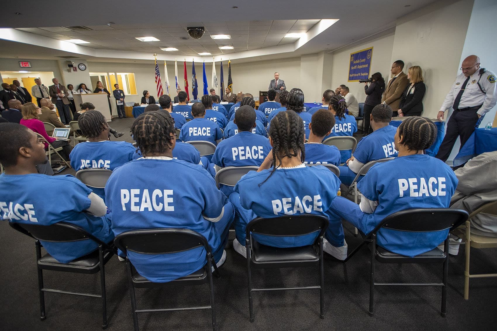 Inmates of the PEACE unit at the Suffolk County Correctional Facility listen as Michael Harris speaks about the PEACE unit. (Jesse Costa/WBUR)