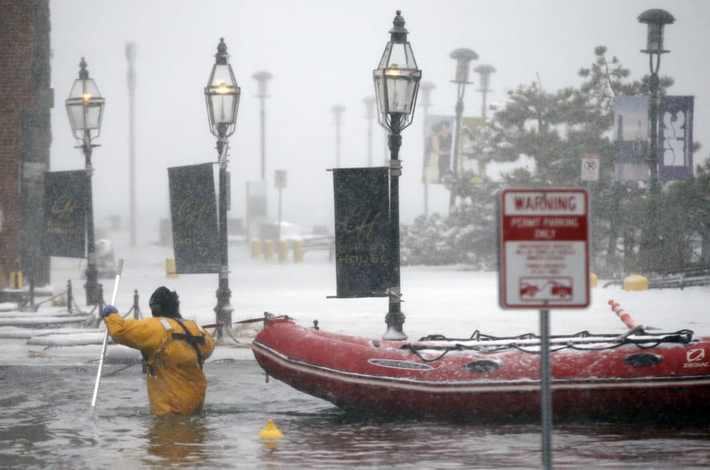 In this Jan. 4, 2018 file photo, a Boston firefighter wades through waters from Boston Harbor that flooded onto Long Wharf in Boston. (Michael Dwyer/AP)
