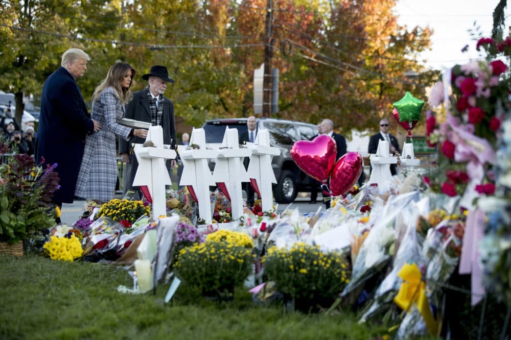 First lady Melania Trump, accompanied by President Donald Trump, and Tree of Life Rabbi Jeffrey Myers, right, places a white flower at a memorial for those killed at the Tree of Life Synagogue in Pittsburgh, Tuesday, Oct. 30, 2018. (AP Photo/Andrew Harnik)