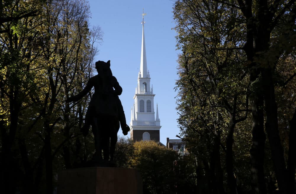 In this Wednesday, Nov. 7, 2018 photo Old North Church stands behind a statue of Paul Revere in the North End neighborhood of Boston. A bronze wreath and plaque that forms part of a memorial, which includes thousands of dog tags honoring soldiers killed in Iraq and Afghanistan, has been installed on the grounds of the church. The new plaque and wreath help explain the meaning of the dog tags and acknowledge Britain's contribution and sacrifice. (Steven Senne/AP)