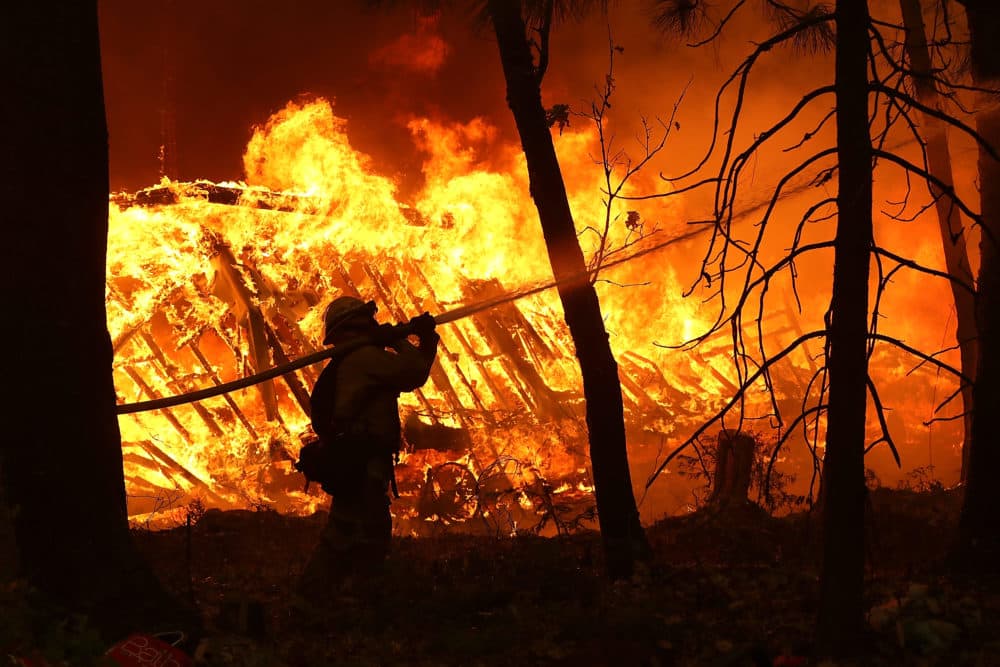 A Cal Fire firefighter sprays water on a home next to a burning home as the Camp Fire moves through the area on Nov. 9, 2018 in Magalia, Calif. (Justin Sullivan/Getty Images)