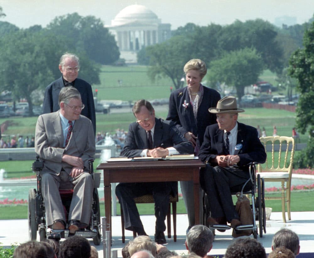 President George H.W. Bush signs the Americans with Disabilities Act during a ceremony on the South Lawn of the White House on July 26, 1990. (Barry Thumma/AP)