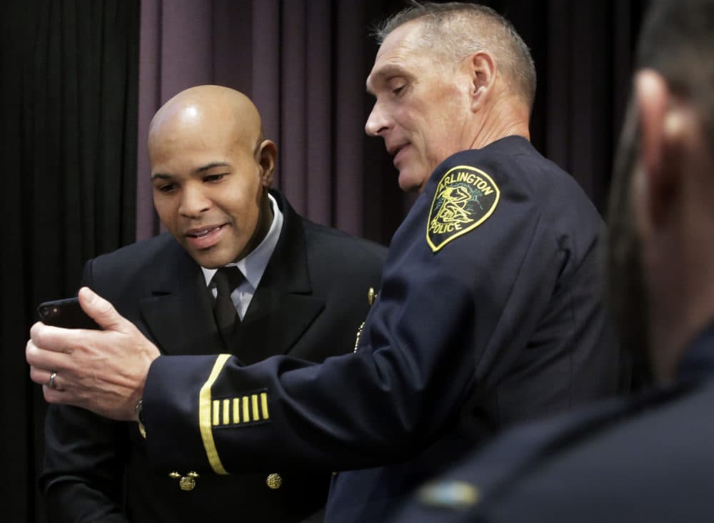 United States Surgeon General Jerome Adams, left, and Arlington, Mass., Police Chief Frederick Ryan, center, look at a mobile phone during a break at a national summit focused on police efforts to address the opioid epidemic on Thursday. (Steven Senne/AP)