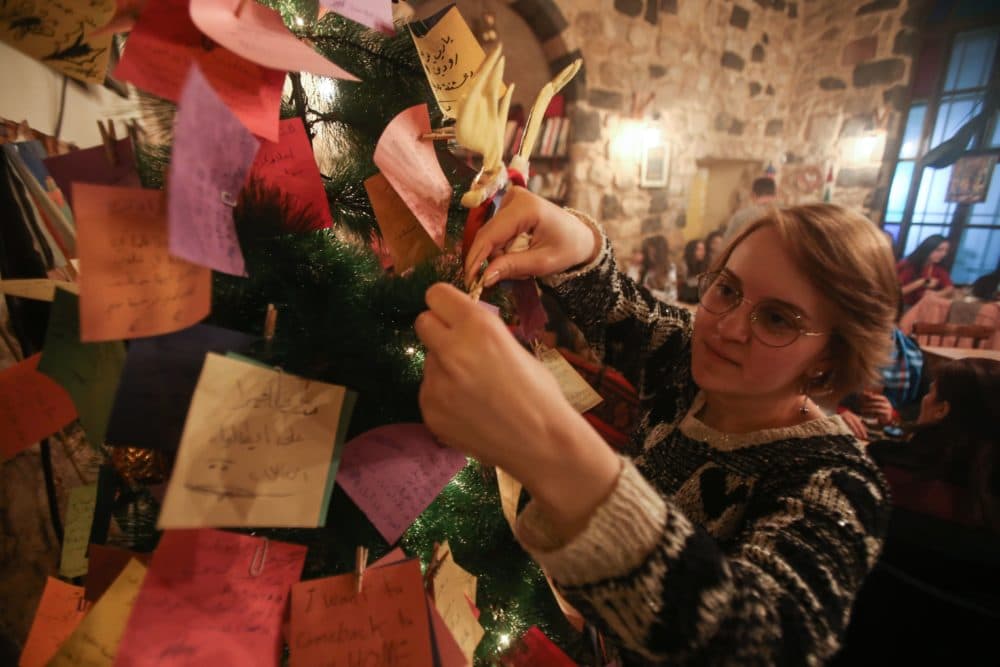 A Syrian youth hangs on a Christmas tree New Year wishes written on a card in a coffee shop in the Syrian capital Damascus on Dec. 17, 2017. (Youssef Karwashan/AFP/Getty Images)