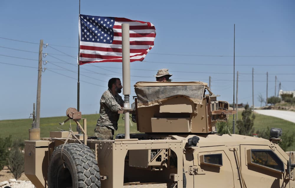 In this April 4, 2018 photo, a U.S-backed Syrian Manbij Military Council soldier, left, speaks with a U.S. soldier, at a U.S. position near the tense front line with Turkish-backed fighters, in Manbij town, north Syria. President Donald Trump's decision to withdraw troops from Syria has rattled Washington's Kurdish allies, who are its most reliable partner in Syria and among the most effective ground forces battling the Islamic State group. (Hussein Malla/AP)