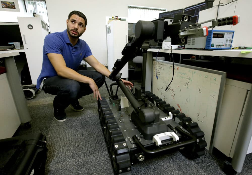 In this Aug. 28, 2018 photo, software engineer Nicholas Otero, of Woburn, Mass., speaks with a colleague about features on a Centaur robot, right, at Endeavor Robotics in Chelmsford, Mass.  The Army is looking for a few good robots. These robots won’t fight, at least not yet. But they will be designed to help the men and women who do. The companies making them are waging a different kind of battle. At stake is a contract worth almost half a billion dollars for 3,000 backpack-sized robots that can defuse bombs and scout enemy positions. (Steven Senne/AP)